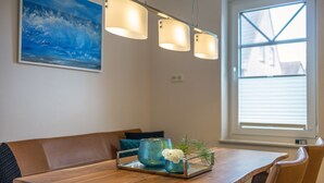Un comedor con mesa de madera, banco y lámpara colgante.
