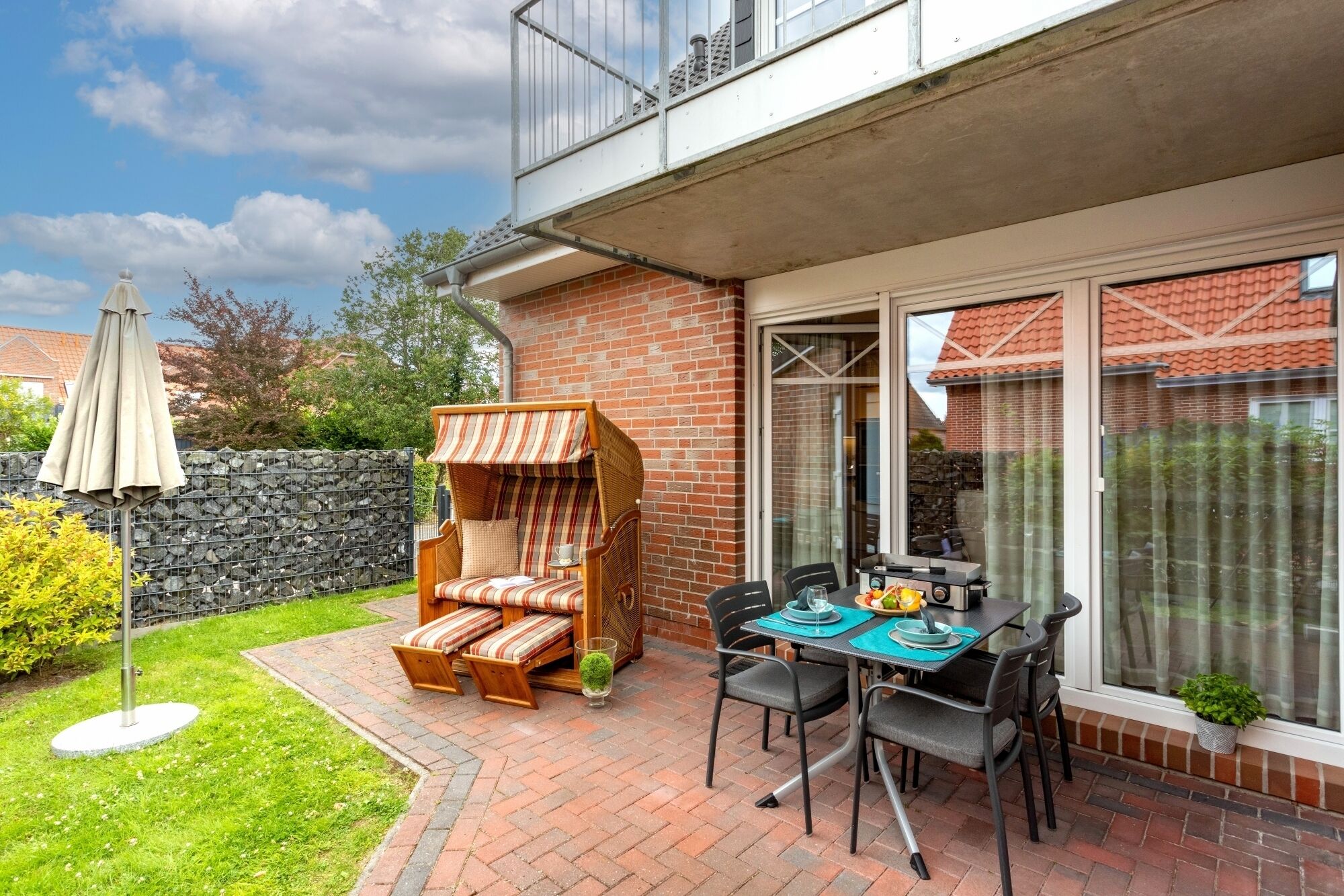 Une terrasse avec un banc en bois, une table avec des chaises et une plante en pot.