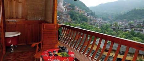 A wooden balcony with a view of a village and mountains.