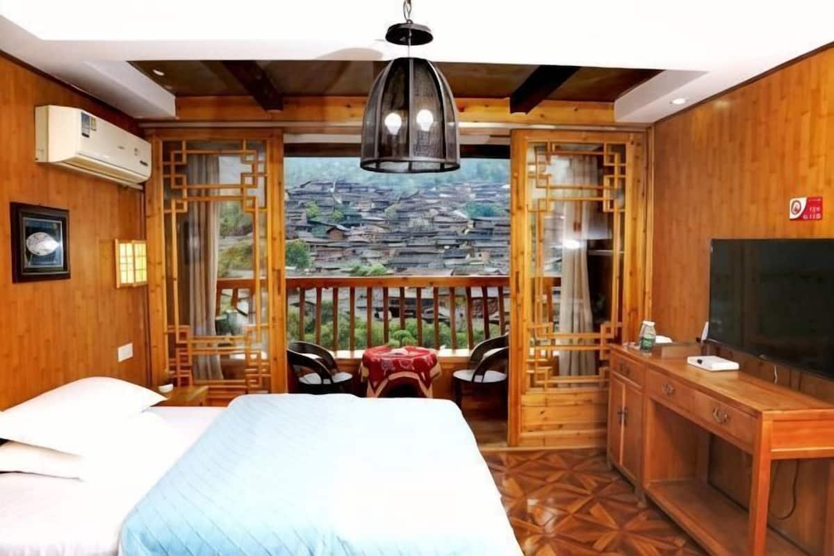 A bedroom with a bed, a desk, a chair, and a TV.