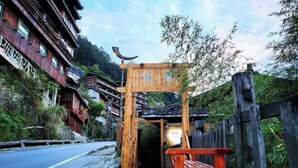 A wooden entrance with a bench, a street, and traditional buildings.