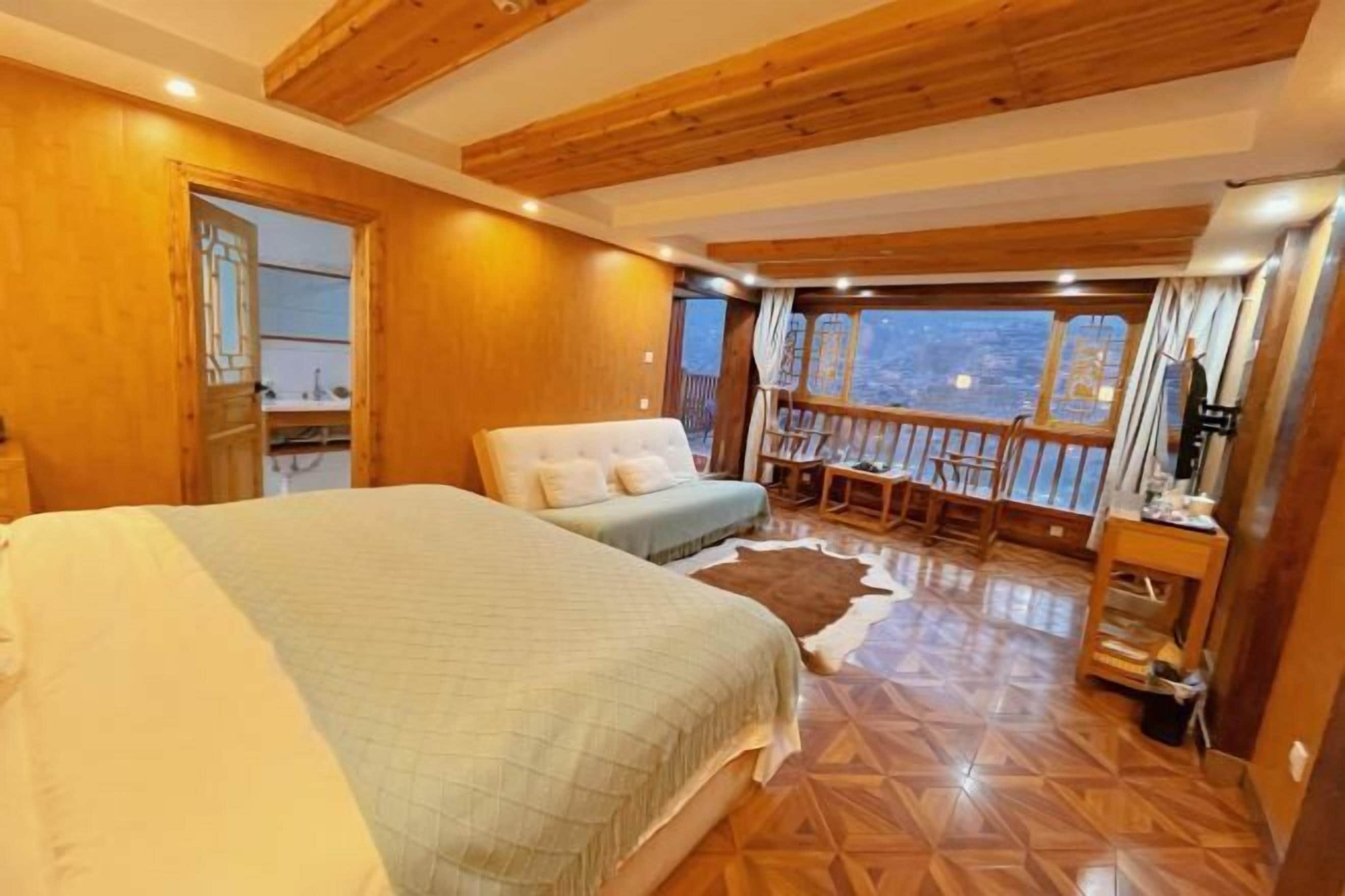 Quarto com uma cama grande, uma cama menor, teto de madeira, vista para o exterior e piso de madeira.