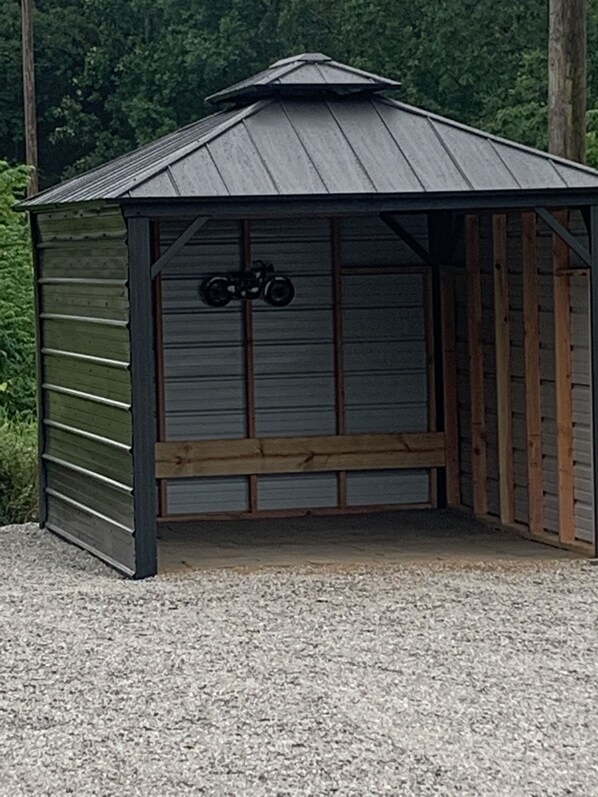 Un petit abri de plain-pied, doté d’un toit en pente et d’un banc en bois à l’intérieur.