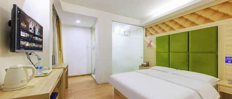 Une chambre d’hôtel équipée d’un lit, d’un bureau avec une bouilloire, d’une télévision et d’un climatiseur fixé au mur.