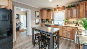 Una cocina moderna con armarios de madera, una isla central con taburetes y un horno empotrado.