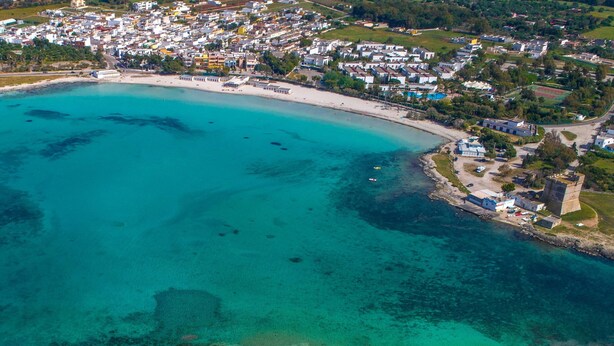 An aerial view of a coastal town with a beach, clear turquoise waters, and residential buildings. - 3193 Appartamento Vittoria by Barbarhouse (Nardò)