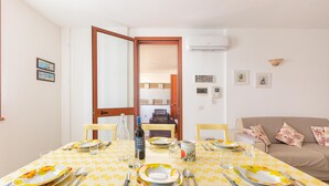 A dining area with a table set for four, a sofa, and a door leading to another room. - 3193 Appartamento Vittoria by Barbarhouse (Nardò)