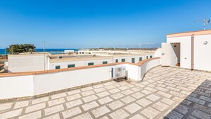 A rooftop terrace with a clear view of the sea, a white building with a red roof, and a tiled floor. - 3193 Appartamento Vittoria by Barbarhouse (Nardò)
