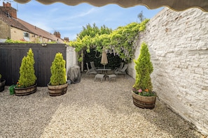 A patio with a table and chairs, surrounded by potted plants and a white brick wall. - Cozy Lodge Sleeps 4 in Barton-upon-humber (Barton-upon-Humber)