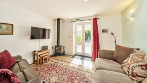 A living room with a sofa, a television, a fireplace, and a door leading outside. - Cozy Lodge Sleeps 4 in Barton-upon-humber (Barton-upon-Humber)