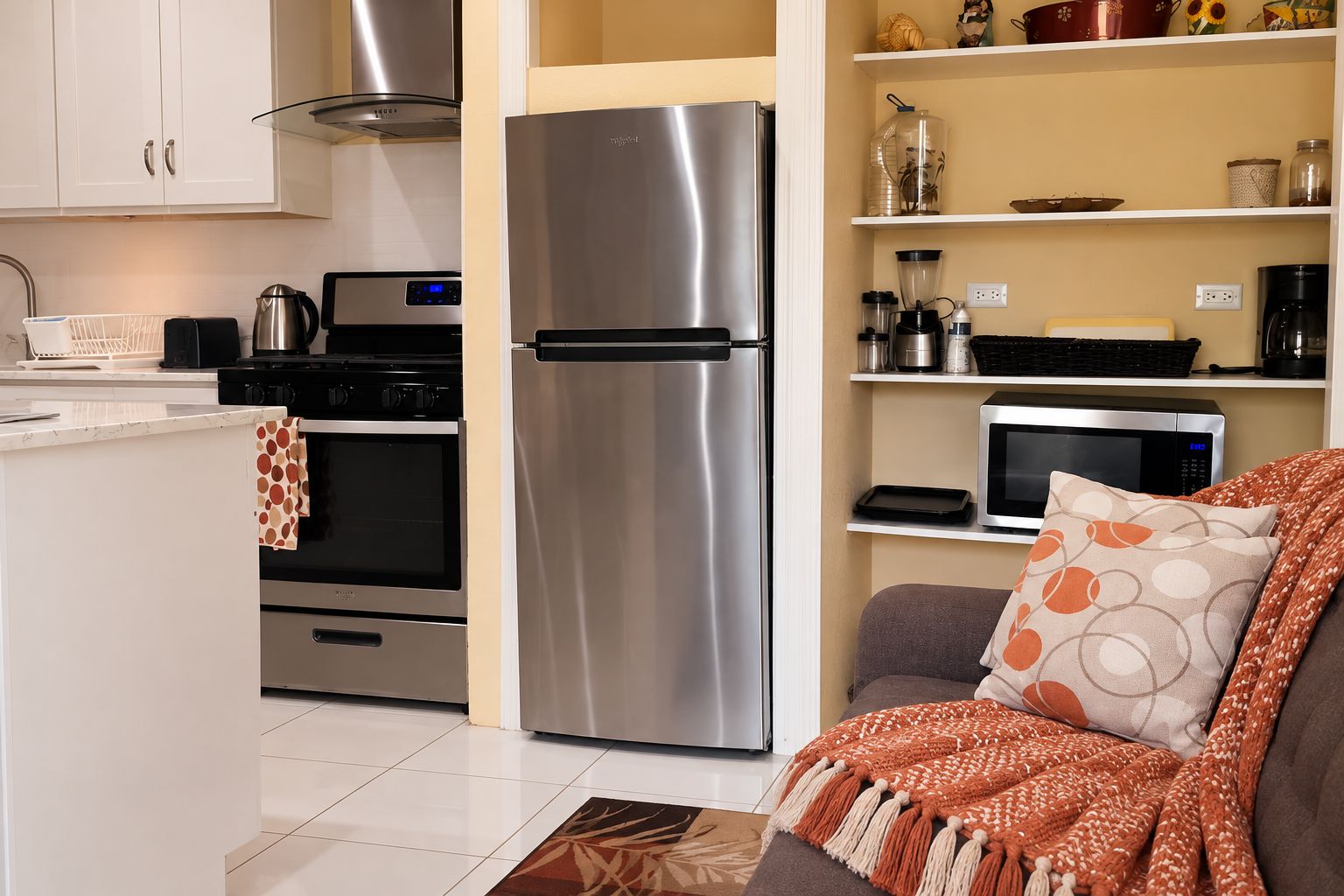 Una cocina compacta con refrigerador, horno y microondas de acero inoxidable.