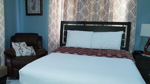 Een slaapkamer met een bed, een stoel en een nachtkastje.
