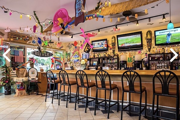 Eine Bar mit mehreren Fernsehern, einer Theke und einigen Sesseln.