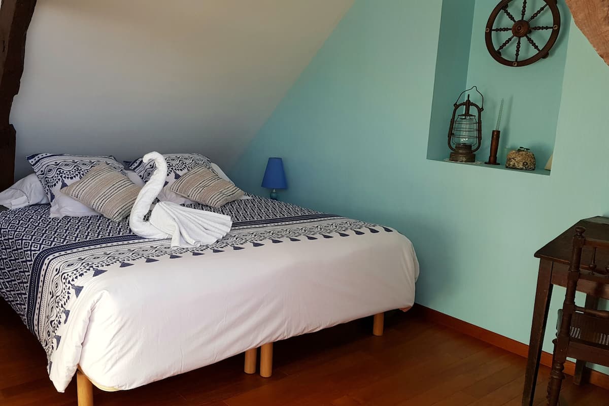 A neatly made bed with patterned bedding, a wooden nightstand with a lamp, and a rustic wall decor.