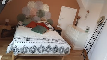 Une chambre à coucher avec un lit, une commode, une table de chevet, une lampe et une échelle.