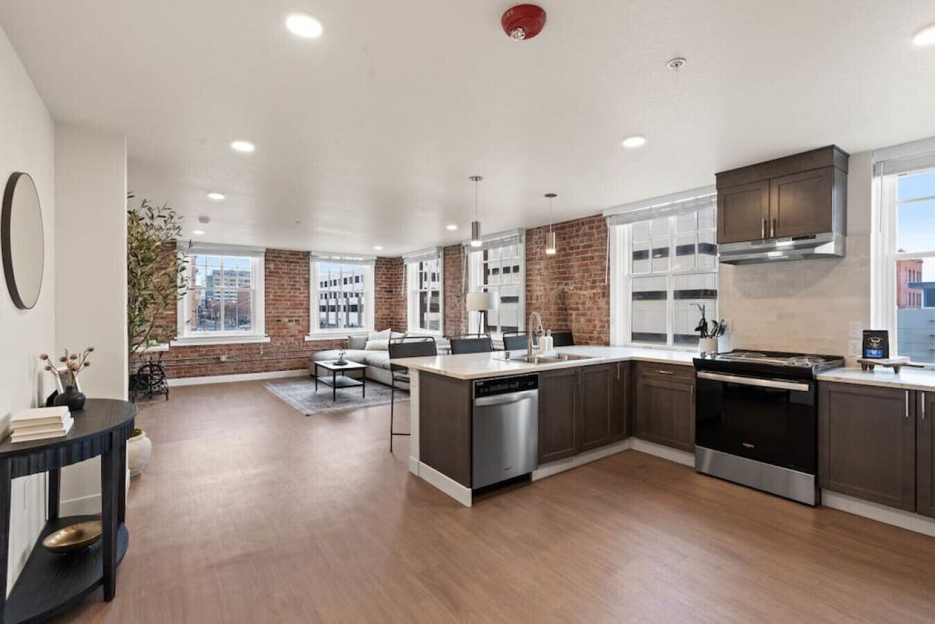 A modern kitchen with a large island, dark cabinetry, and a view of the city through large windows.