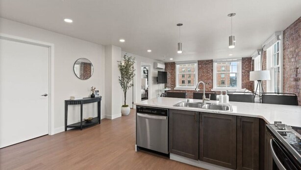 Una cocina moderna con una isla central, electrodomésticos integrados y una pared de acento de ladrillo.