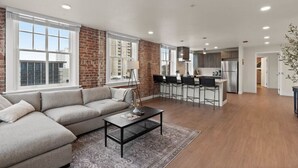 Amplia sala de estar con un sofá grande, una mesa de centro y una cocina con barra y electrodomésticos modernos.