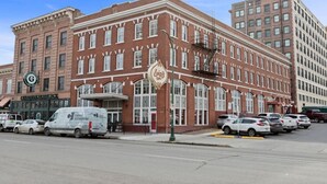 A historic brick building with a prominent 'Luigi's' sign, a Guardian Mortgage office, and parked cars on the street. - King Bed! J & K on Main Luxury Apartment 302 (Spokane)