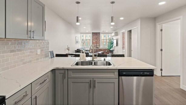 A modern kitchen with a central island, stainless steel appliances, and a dining area in the background.