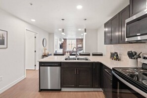 A modern kitchen with dark cabinetry, a stainless steel dishwasher, and a gas stove.