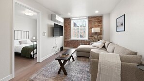 Ein modernes Wohnzimmer mit einer Couch, einem Couchtisch und einem an der Wand befestigten Fernseher.