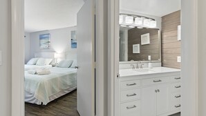 Une chambre d’hôtel avec un lit, une salle de bain comprenant un lavabo et un miroir, et une vue sur l’extérieur.