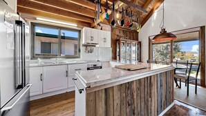 A modern kitchen with white cabinets, stainless steel appliances, and a wooden ceiling. - Aarlaur 2 - Charming 2BR Rustic Home l Bath l Fire Pit l WiFi Air-Con (Jindabyne)