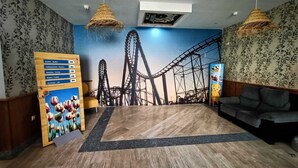 Una habitación con un mural de montañas rusas, suelo de madera, un sofá y un letrero de indicaciones.