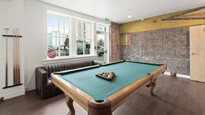 A pool table in a room with a brick wall and a window overlooking a cityscape. - Spacious Apartment with King Beds!  J&K on Main (Spokane)