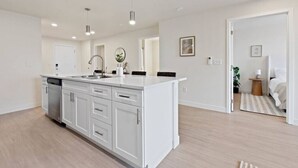 Una cocina moderna con armarios blancos, una isla central e iluminación colgante.