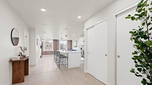 Una cocina moderna con una isla central, muebles blancos y una pared de ladrillo decorativa.