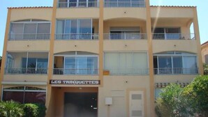 Un immeuble à plusieurs étages, doté de balcons et d’une enseigne sur laquelle on peut lire « LES TRIN QUETTES ».