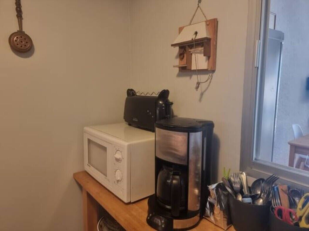 Une petite cuisine équipée d’un four à micro-ondes, d’une machine à café et d’un petit placard.