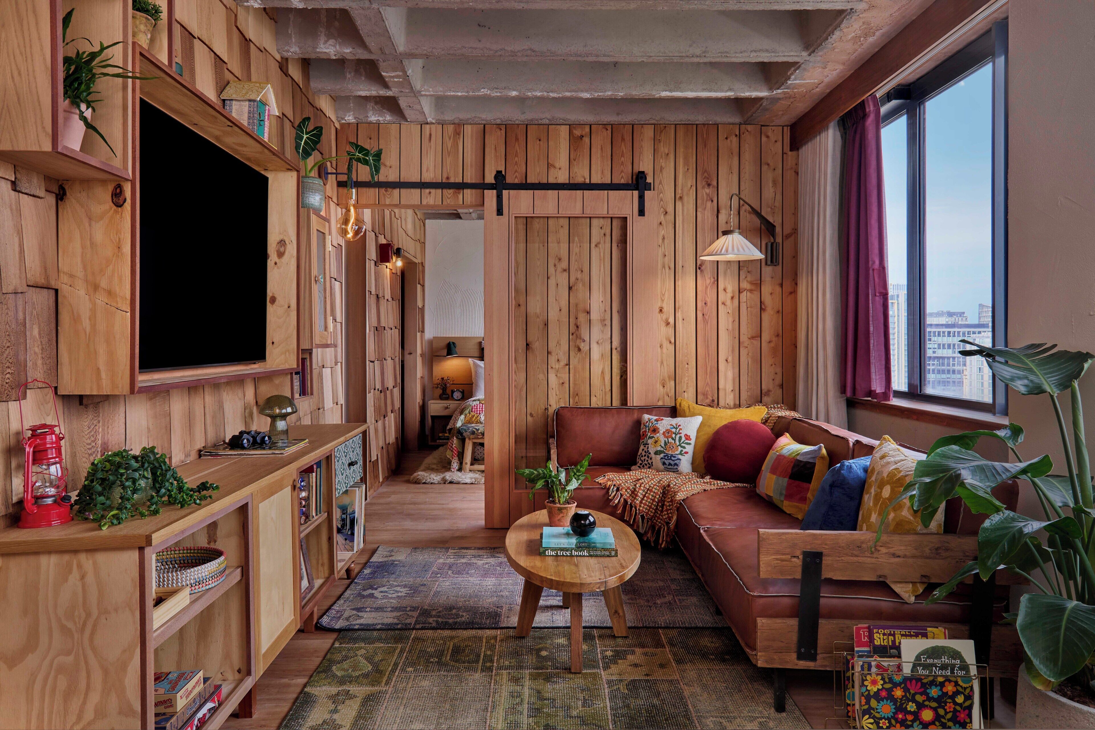 Ein gemütliches Wohnzimmer mit Holzwänden, einem großen Fenster, einem Sofa und einem Couchtisch.