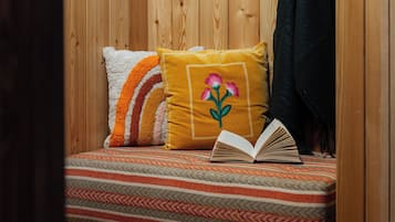 Ein Zimmer mit Holzwänden, einem Bett, Kissen, einer Decke und einem offenen Buch.