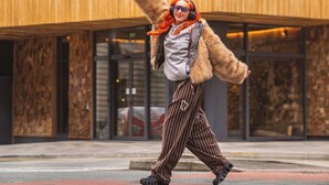 A person in a fur coat and striped pants walking in front of a building with a sign that reads "treehouse hotel". - Treehouse Hotel Manchester (Manchester)