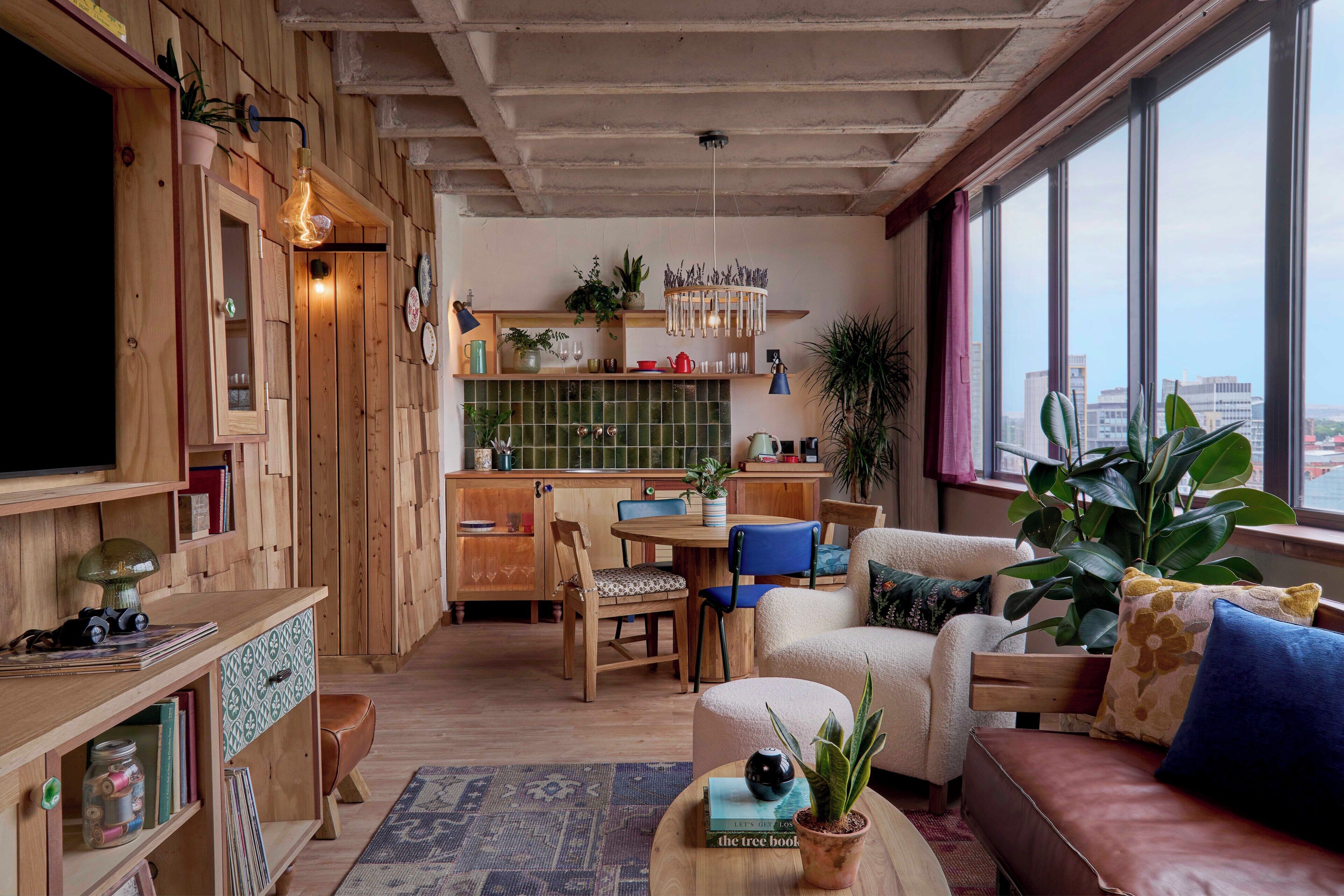 Un salon chaleureux, doté de meubles en bois, d’un coin repas et offrant une vue sur la ville grâce à de grandes fenêtres.