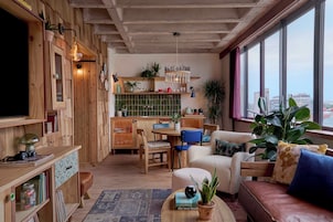 Una sala de estar acogedora con muebles de madera, un comedor y vistas a la ciudad a través de amplios ventanales.
