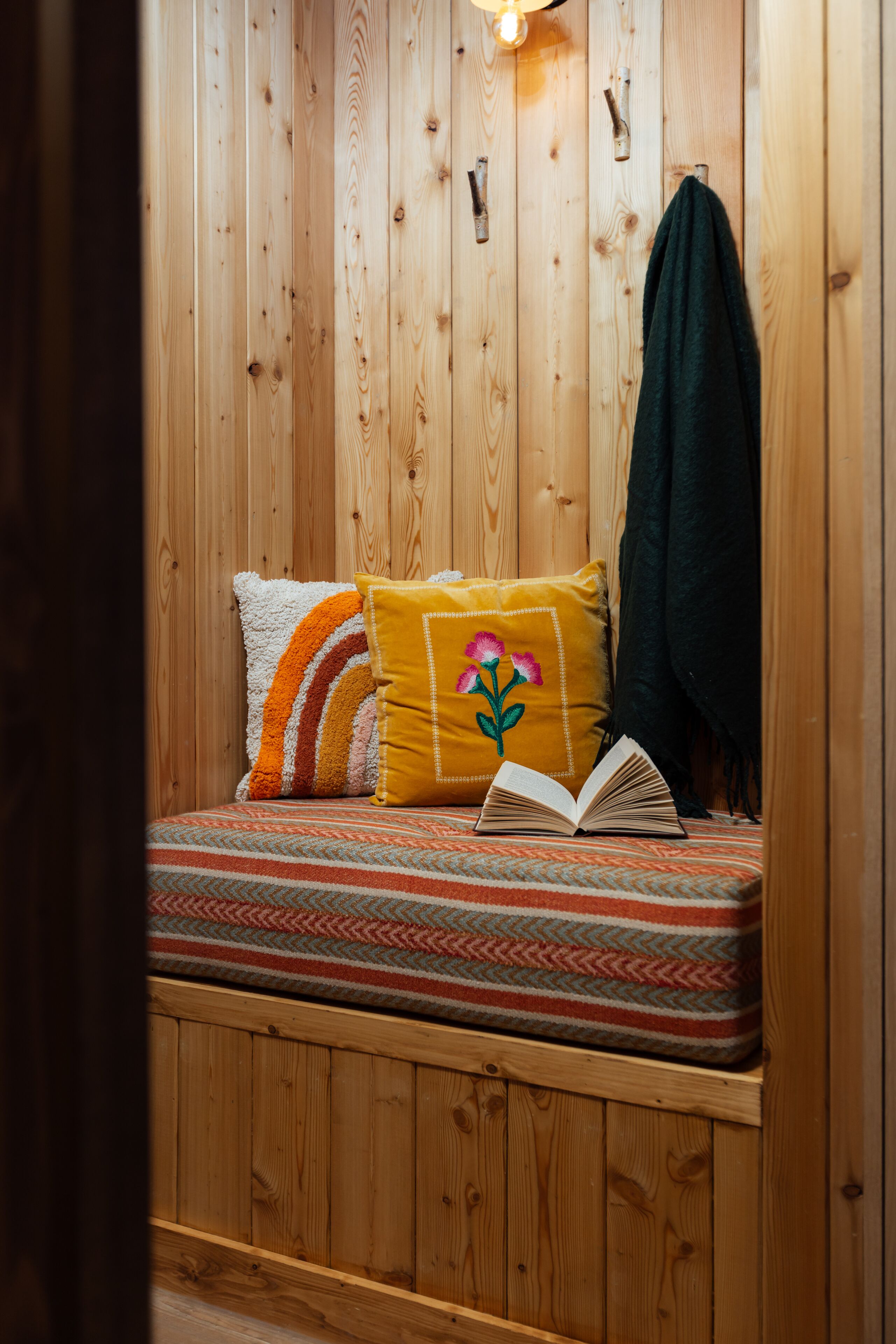 A wooden cabin-style room with a bed, pillows, and a book.