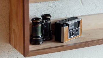 A wooden shelf with two vintage cameras and a pair of binoculars.