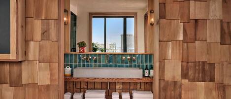 Un baño con diseño de pared de madera, un espejo grande, una ventana y un lavabo con salpicadero de azulejos.