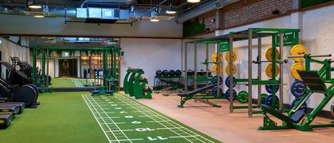 A gym with treadmills, weightlifting equipment, and a green turf track.