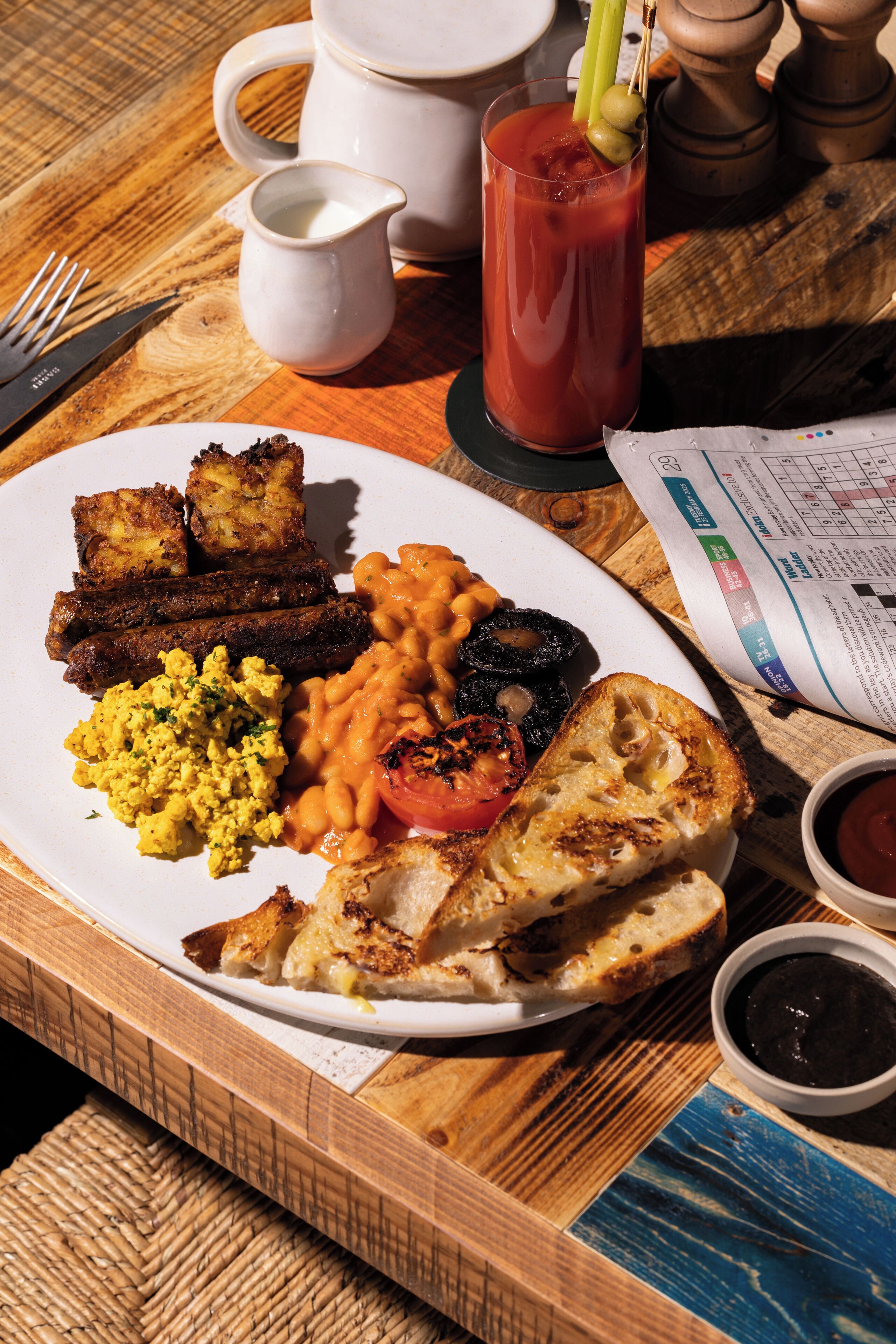 A breakfast plate with eggs, sausages, beans, toast, and a Bloody Mary.