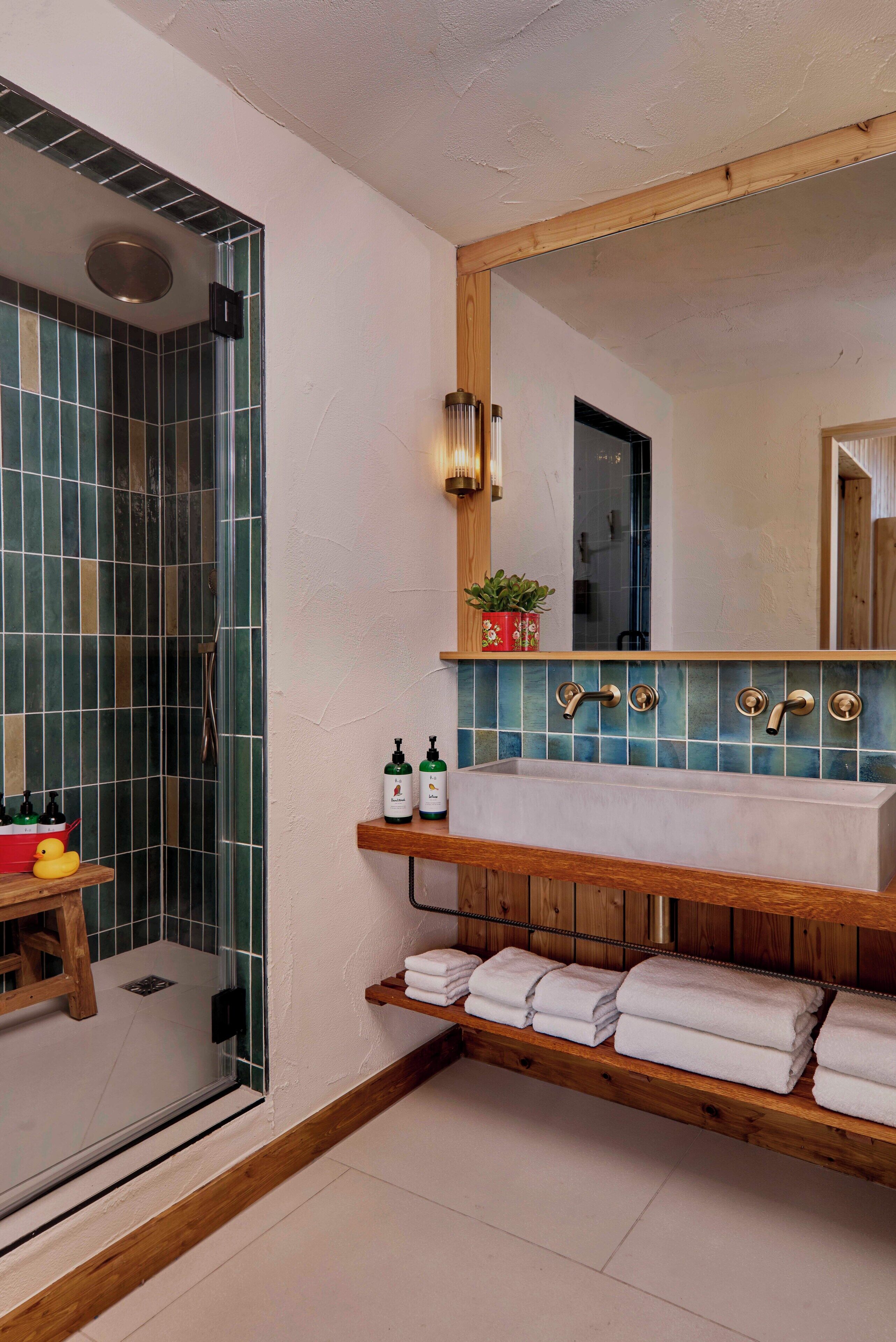 Une salle de bain moderne avec une douche à parois de verre, un meuble-lavabo en bois avec un miroir et une étagère pour les serviettes.