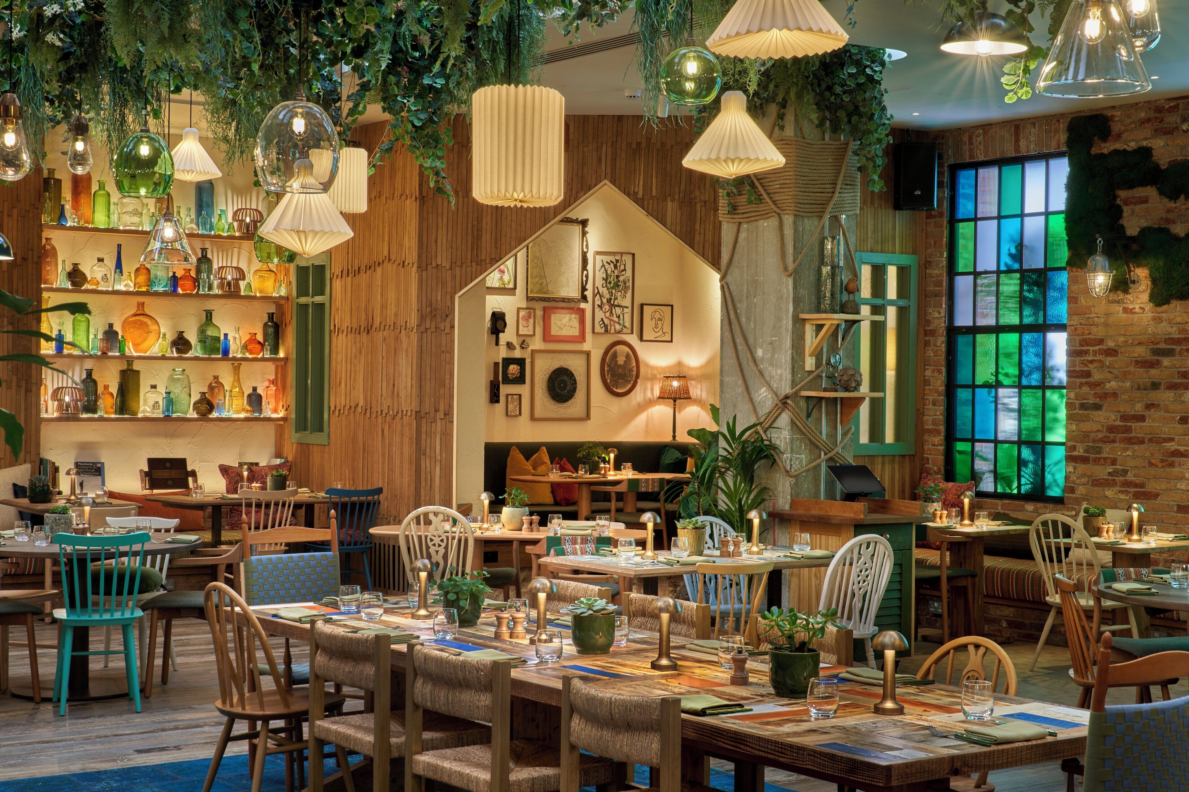 A restaurant with wooden walls, hanging plants, and various table settings.