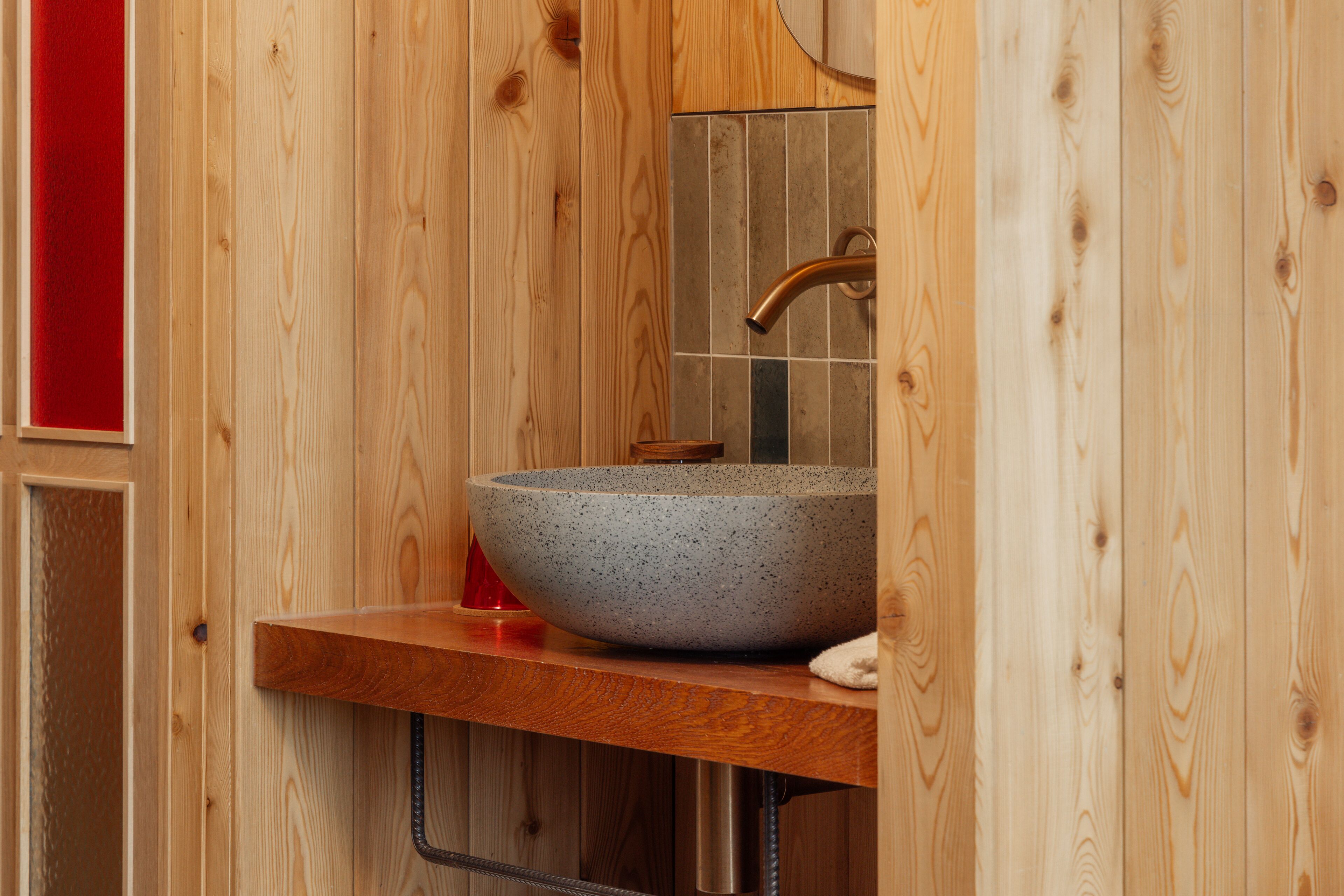 A wooden interior with a stone sink and a mirror above it.