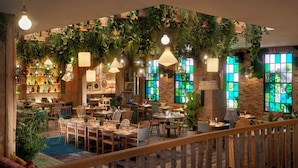 A cozy restaurant with wooden furniture, hanging plants, and green-tinted windows. - Treehouse Hotel Manchester (Manchester)