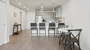 Une cuisine moderne avec des meubles blancs, un îlot central et des luminaires suspendus.