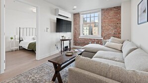 A modern living room with a sofa, a coffee table, and a TV mounted on the wall.